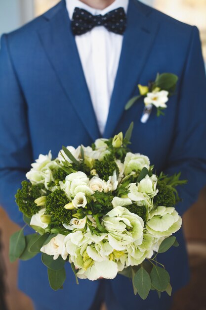 Lo sposo detiene il bouquet da sposa di fiori