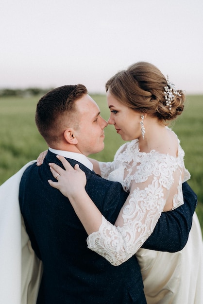 Lo sposo e la sposa camminano lungo il campo di grano verde in una giornata luminosa