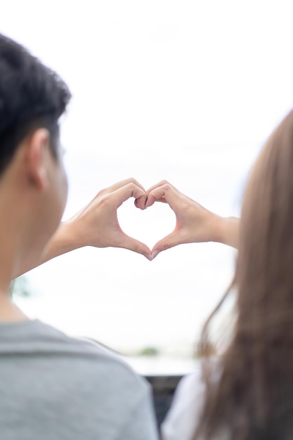 Lo sposo e la sposa coordinano la loro mano insieme per creare la forma del CUORE con il cielo limpido