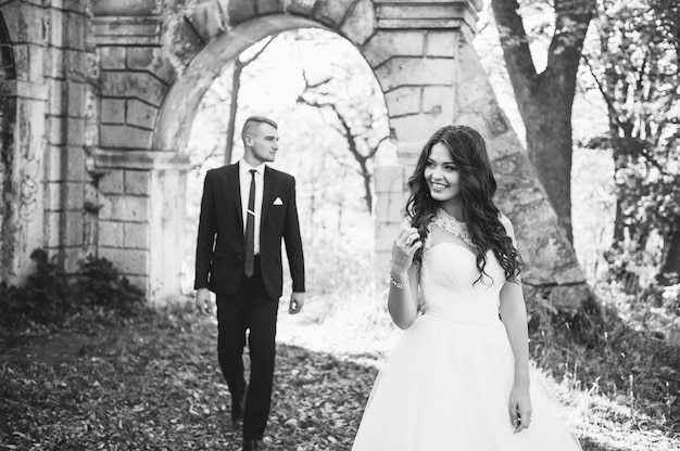 Lo sposo e la sposa felici e innamorati camminano nel parco in autunno il giorno delle nozze