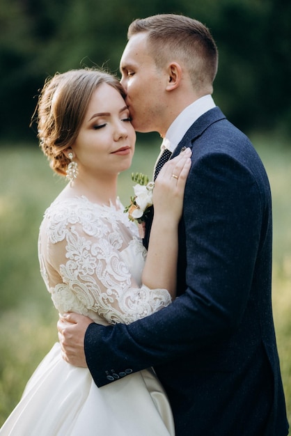 Lo sposo e la sposa stanno camminando nella foresta vicino a un fiume stretto in una giornata luminosa