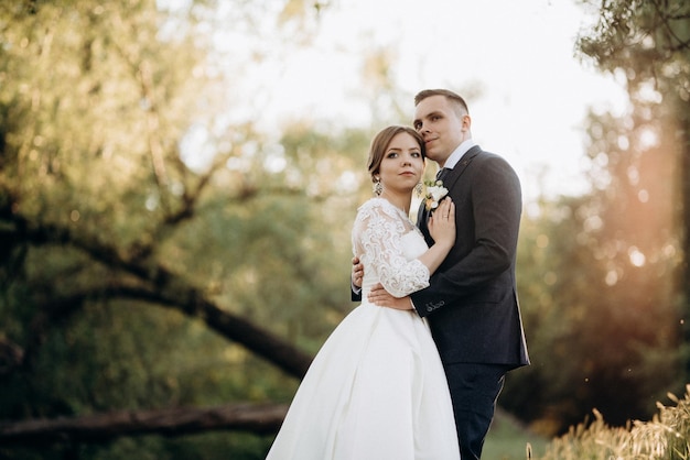 Lo sposo e la sposa stanno camminando nella foresta vicino a un fiume stretto in una giornata luminosa