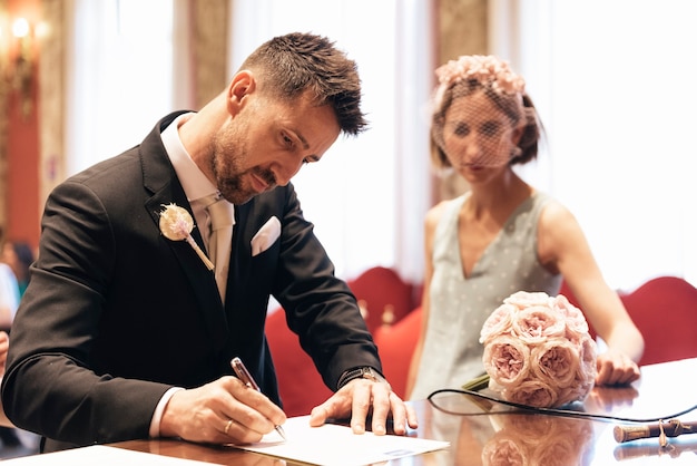 Lo sposo firma le carte del matrimonio