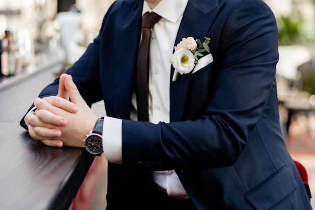 Lo sposo in giacca e cravatta è seduto al bar in attesa della sposa al matrimonio