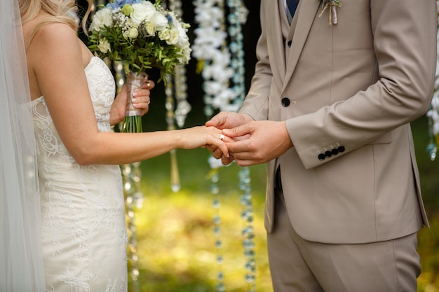 Lo sposo indossa l'anello al dito della sposa, alla cerimonia nuziale