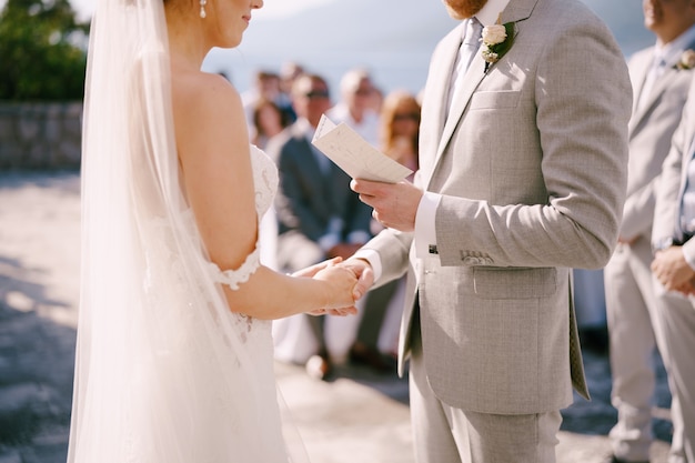 Lo sposo legge un voto dalla carta alla sposa che le tiene la mano