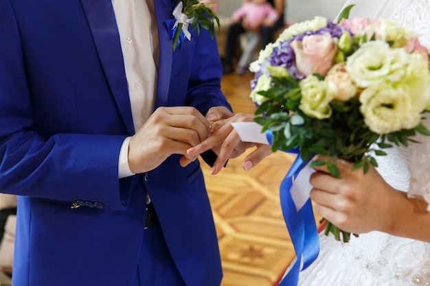 Lo sposo mette un anello al dito della sposa durante la cerimonia di nozze