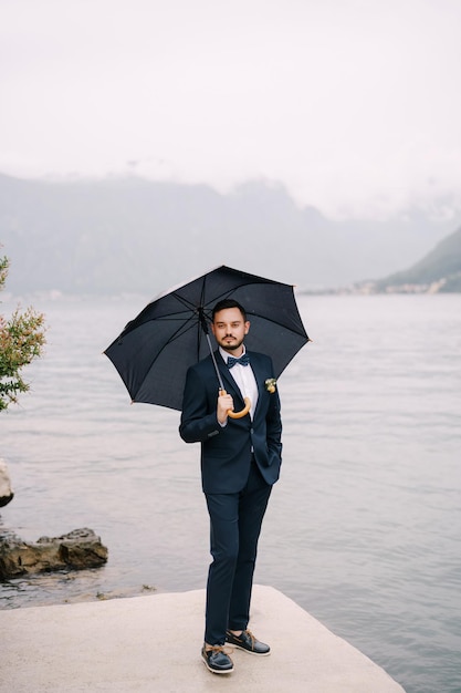 Lo sposo sta sotto un ombrellone sul molo vicino all'acqua