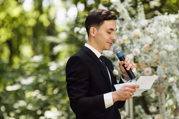 Lo sposo sta vicino all'altare. cerimonia di matrimonio dove lo sposo felice aspetta la sposa. giorno del matrimonio. sposo in abito nero alla cerimonia di uscita