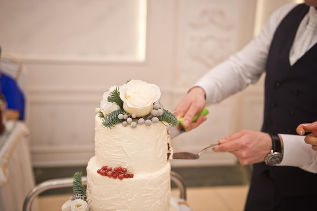 Lo sposo taglia una bellissima torta nuziale con fiori e bacche 2524