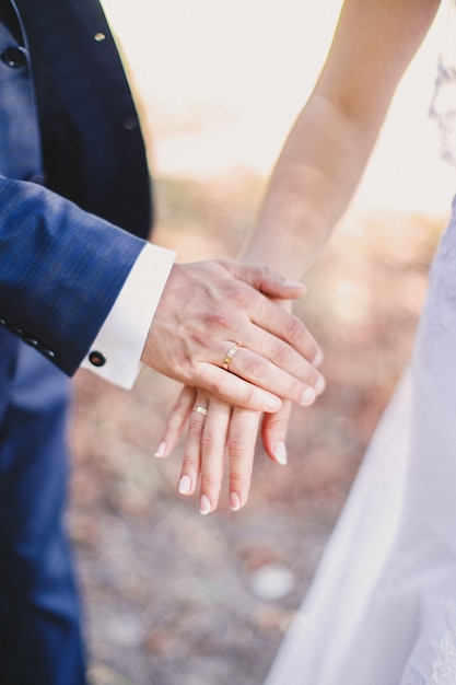 Lo sposo tiene la mano della sposa in vestito bianco.