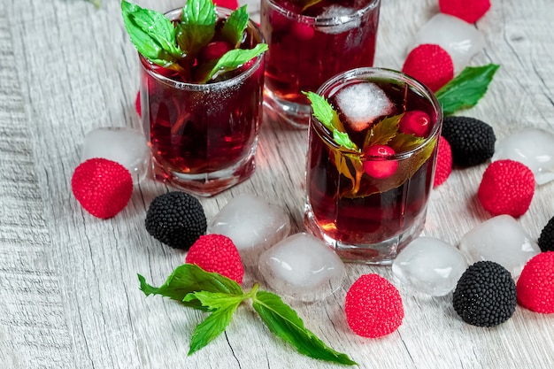 Lo stemware rosso ha sparato il cocktail freddo alcolico con i mirtilli lamponi limone e menta