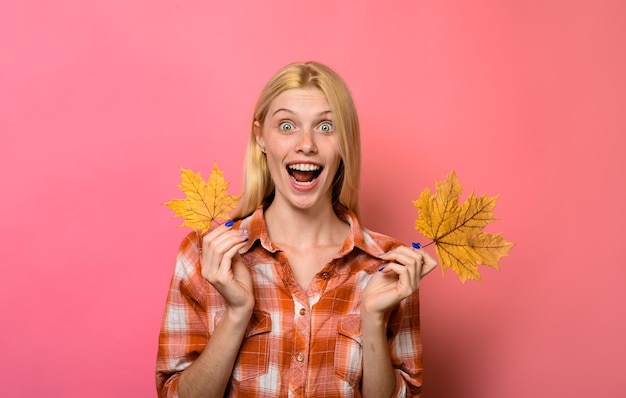 Lo stile di vita dell'umore autunnale e il concetto autunnale di una donna sorridente tiene in mano una donna con foglie d'acero gialle