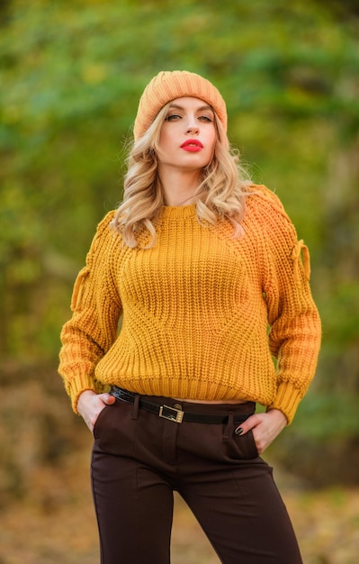 Lo stile è una questione di equilibrio. La donna indossa un maglione caldo sullo sfondo della natura sfocato. Passeggiata nel parco autunnale. La ragazza operata indossa un maglione lavorato a maglia. Splendida signora sentirsi a proprio agio in maglione di lana. Vestiti alla moda.