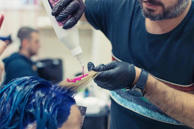 Lo stilista del parrucchiere fa la colorazione dei capelli di una donna nel salone del parrucchiere