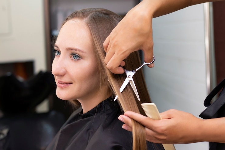 Foto lo stilista professionista taglia i capelli femminili in salone