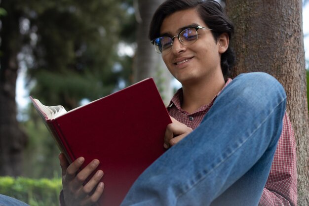 Lo studente con gli occhiali si diverte a leggere il suo libro con un sorriso