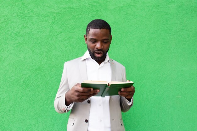 Lo studente con un libro su una parete verde