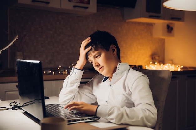 Lo studente si prepara per l'esame a tarda notte. un adolescente si siede a un laptop ed è impegnato a tarda sera.