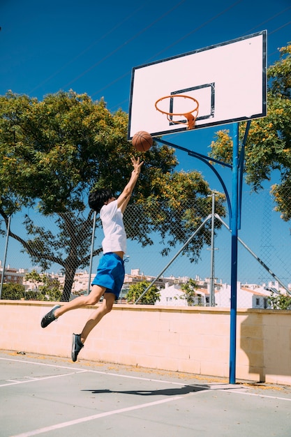 Lo studente teenager maschio che fa la pallacanestro salta il colpo