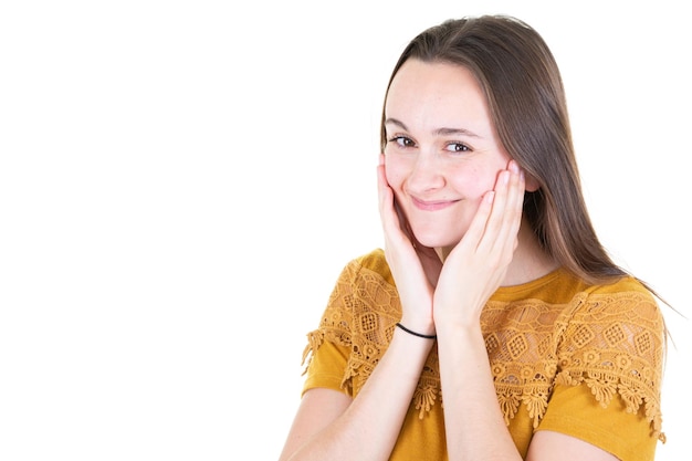 Lo studio del primo piano ha sparato il modello della giovane e bella donna che guarda l'obbiettivo con un sorriso carino affascinante mentre posa contro lo sfondo bianco dello spazio della copia in bianco