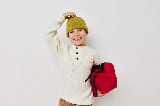 Lo zaino della scuola della bambina con un cappello sulla sua testa ha isolato lo sfondo