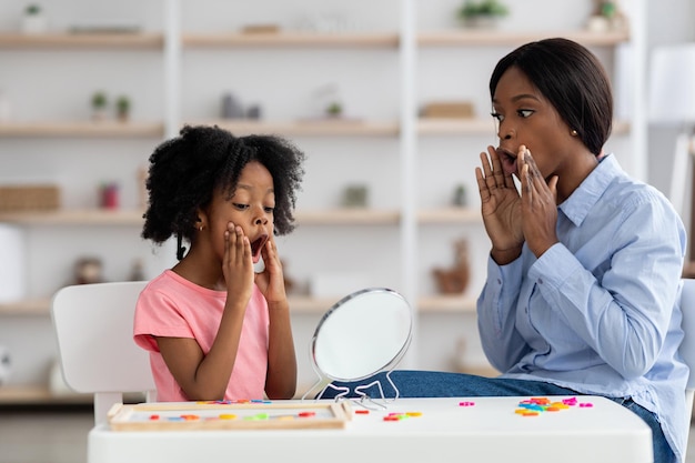 Logopedista femminile che si esercita con una bambina adorabile