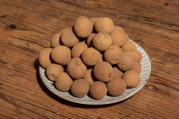 Longan essiccato nel contenitore sul tavolo con venature del legno