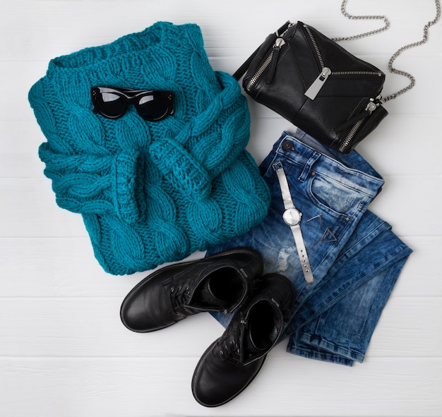 Look piatto femminile dallo stile casual con caldo maglione turchese, stivali, jeans, borsa, orologio e occhiali da sole