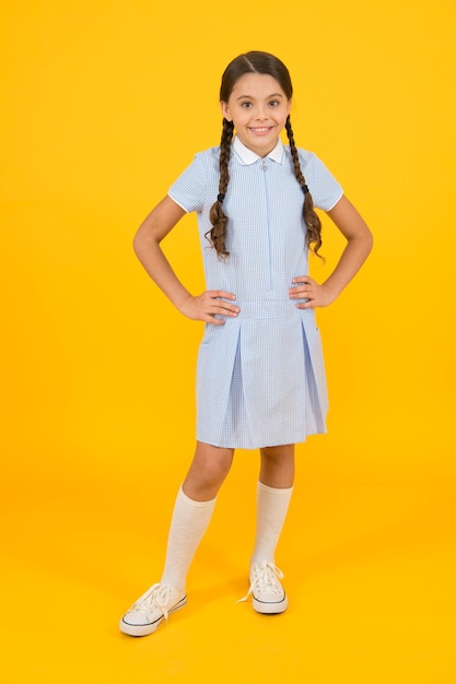 Look retrò bambino in stile vintage vecchia scuola moda bambino bambino felice su sfondo giallo moda e bellezza infanzia felicità umore divertente piccola ragazza in uniforme scolastica scuola moderna