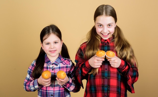 Lotta dei muffin Bambini piccoli sorridenti con muffin di pane veloce Bambine felici che cuociono i muffin per la colazione a casa godendosi il loro gusto di muffin preferito