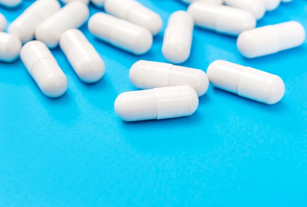 Lotto di capsule bianche su sfondo blu Sfondo medico