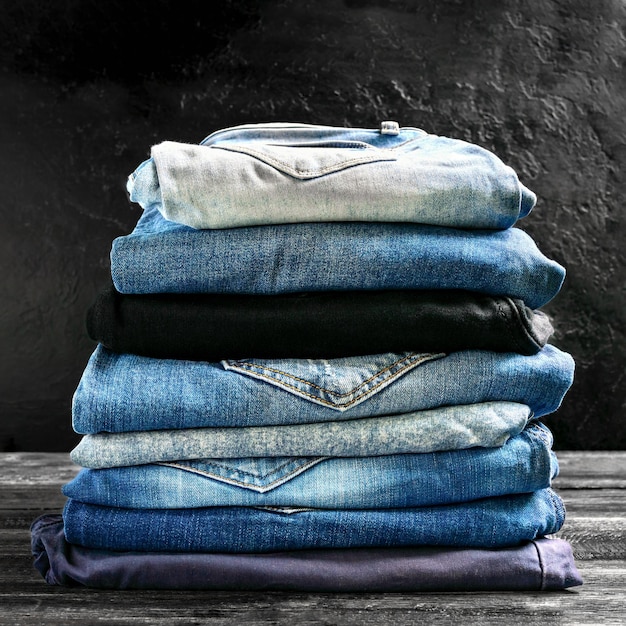 Lotto di jeans diversi in una pila sul tavolo Il concetto di abbigliamento comodo popolare