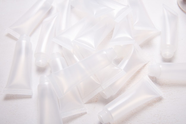 Lotto di tubi vuoti di plastica per lucidalabbra fatto in casa sulla scrivania in legno