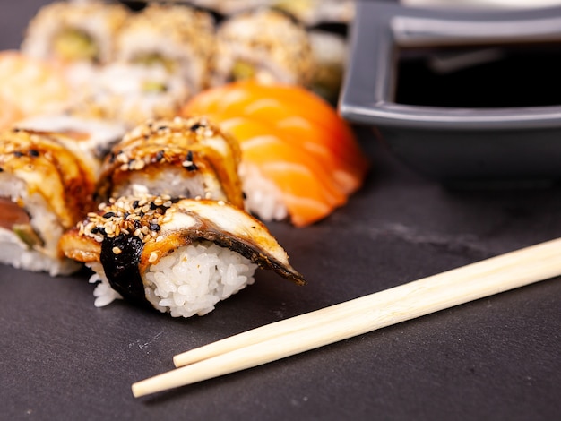 Lotto mix di varietà di rotoli di sushi su sfondo di pietra nera in foto in studio