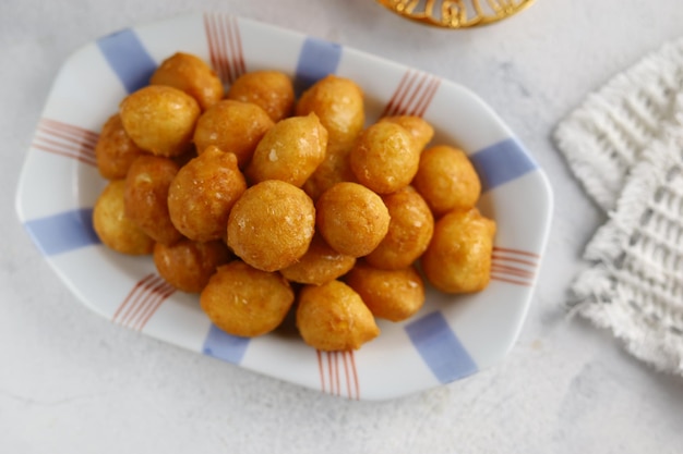 Loukoumades luqaimat o lokma con salsa di miele in un piatto con fondo bianco