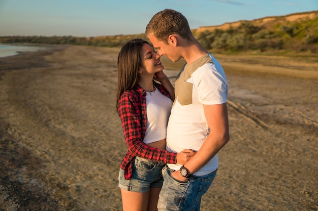 Lovestory di giovane bella coppia sulla spiaggia al tramonto. si stanno baciando