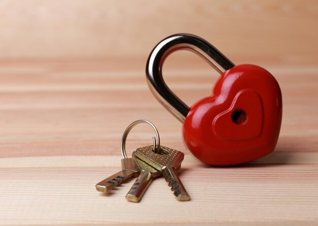 Lucchetto a forma di cuore con chiave su fondo di legno