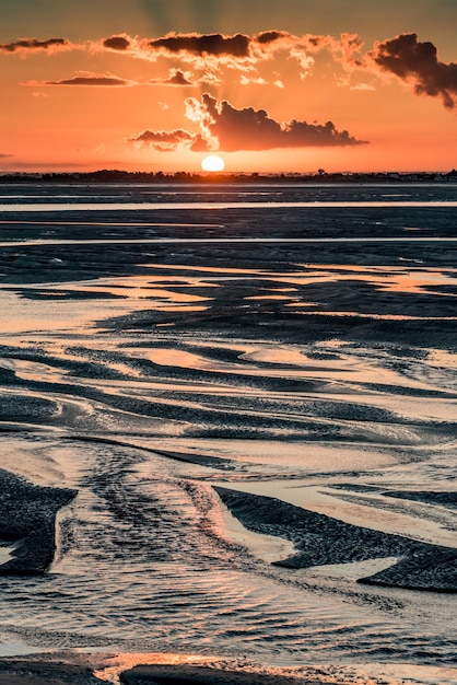 Luce arancione dell'alba sulla foce del fiume Somme Il cielo si riflette nelle pozzanghere