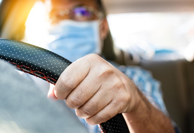 Luce di giorno un uomo che guida con due mani per tenere il volante per controllare l'auto con attenzione mentre la congestione del traffico sfocare un uomo che indossa una maschera per il viso Closeup e selezionare la messa a fuoco sulla mano sfocare lo sfondo