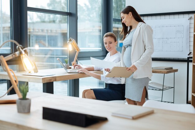 Luce luminosa. Chiuda in su del posto di lavoro con una lampada e un tablet mentre i colleghi positivi hanno una discussione importante