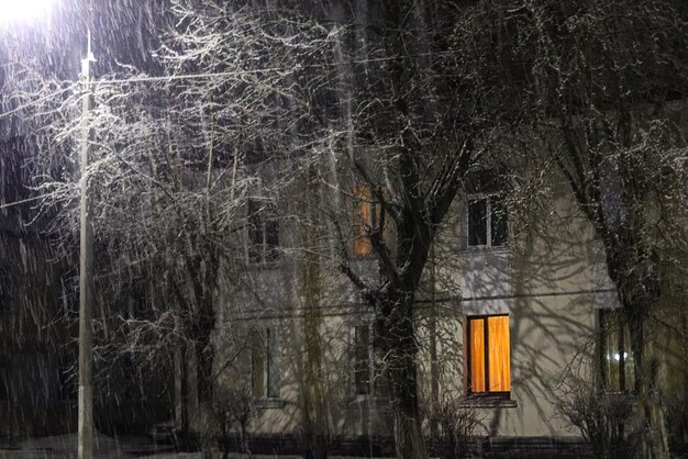 Luce nelle finestre delle case della città in una sera d'inverno durante la nevicata