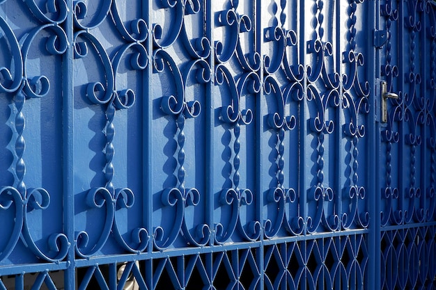 Luce solare e ombra sulla superficie del modello di elementi in ferro battuto della porta del cancello in metallo blu vintage