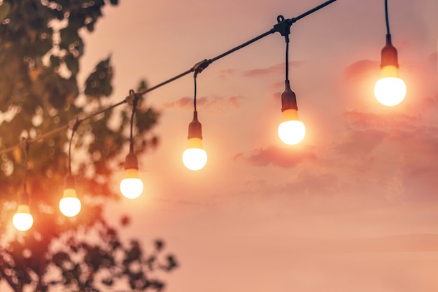 Luce vaga del bokeh sul tramonto con la decorazione gialla delle luci della corda nel ristorante della spiaggia