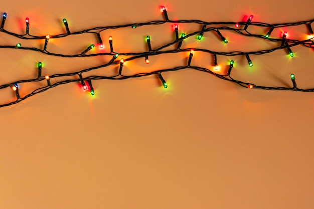 Luci colorate di ghirlanda di Natale su sfondo arancione Luce di Natale con copyspace per la cornice di Capodanno o il layout di Natale Vetrine di decorazioni natalizie