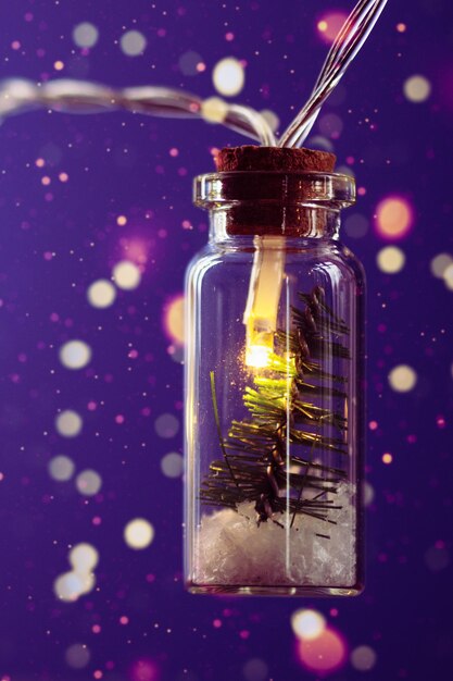 Luci creative della ghirlanda di Natale con bokeh Albero di Natale in un barattolo di vetro con neve