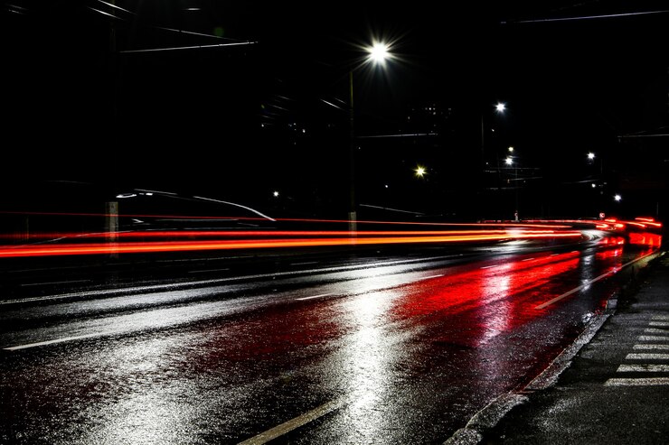 Luci delle auto di notte. Luci stradali. Città notturna. Strada notturna di fotografia a lunga esposizione. Fasce colorate di luce sulla strada. Strada bagnata dopo la pioggia.