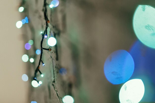 Luci di Natale blu colorate appese al muro primo piano spazio di concetto di carta regalo di Natale per il testo