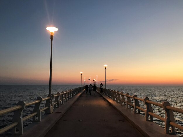 Luci di strada sul molo sul mare contro il cielo durante il tramonto