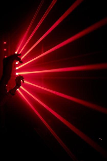 Luci laser al neon rosse luminose illuminano l'oscurità creando linee e forme triangolari in un effetto fantascientifico.